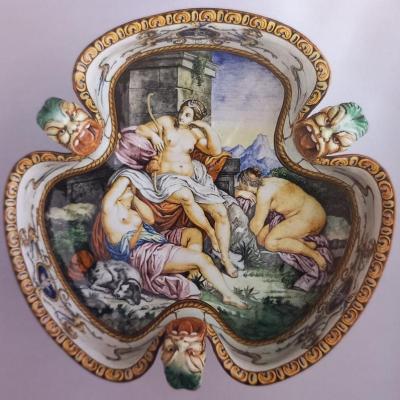 L'immagine centrale è una vasca tribolata, in maiolica dipinto in policromia, all'esterno con motivo di tralci e foglie di viti, all'interno una scena che raffigura "Il riposo di Diana" da fonte non conosciuta circondata da fregi Raffaelleschi. repertorio delle maioliche artistiche di Ginori, esemplare identico è documentato all'esposizione di Parigi del 1867.